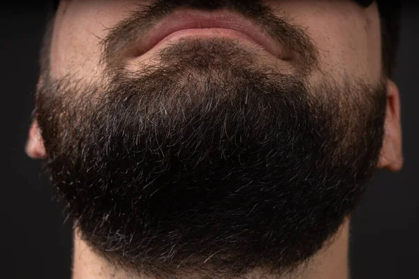 Retrato de un joven barbudo mirando hacia arriba, barbilla vista desde abajo sobre fondo negro aislado. —  Fotos de Stock