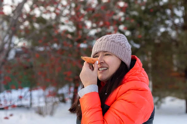 Жінки дорослі кладуть моркву в обличчя, як ніс на задньому дворі будинку, повний снігу ввечері, гуляючи з деревами і залізним парканом на фоні. Батьки проводять час з дітьми — стокове фото