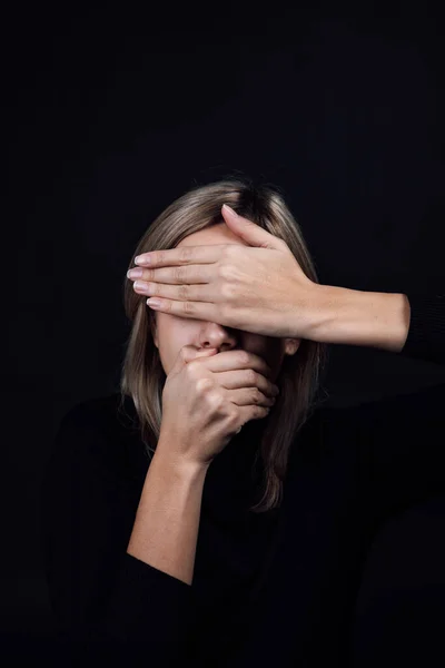 Elleri ve ağzı olan, siyah arka planda siyah bluz giyen ezilmiş bir kadın. Fiziksel ve psikolojik tacize uğramış. İkna edici. Nispeten saldırganlık. Boşluğu kopyala