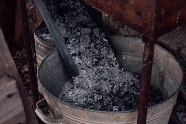 Eski demir kovanın içindeki ahşap küller toprağı gübrelemek için kullanılan paslı brazier 'ın altında. Çevre dostu ve organik döllenme. İnsanlar geleceği düşünüyor.