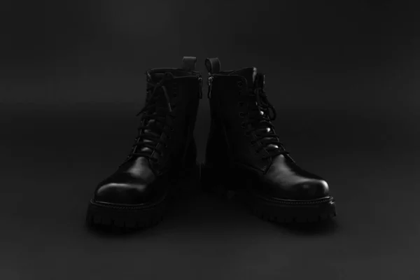 Par de brilhante couro isolado inverno outono unisex botas pretas sobre fundo preto brilhante. Botas com calcanhar bloco, dedo do pé redondo e sola dura em relevo. Espaço de cópia — Fotografia de Stock