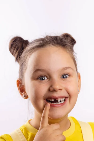 Krásná samice s otevřenými ústy ukazující chybějící přední mléčný zub s prstem na spodním rtu se vzrušeně usmívá na bílém pozadí. První změna zubů jít k zubaři na ošetření zubů — Stock fotografie