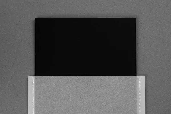 濃いグレーの背景を中心に透明なグレーの紙ケースで製造されたアイテムのための1つの黒の色の段ボールマットブランドラベルタグ。タグモックアップ。スペースのコピー — ストック写真