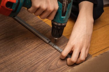 Tornavidayla el sıkışın, demir parçaları koyu kahverengi klasöre vidalayın. Evdeki mobilyaları monte etmek. Uzayı kopyala İnşaat ve tamir araçları kullanılıyor