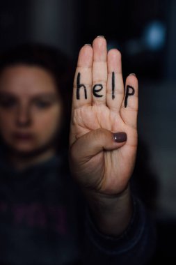 Arka plandaki bulanık genç bayanın parmaklarına yazılmış kelime yardımıyla. Aile içi şiddet belirtisi. Fiziksel, zihinsel, psikolojik taciz. Dövülmüş ve baskı altında. 