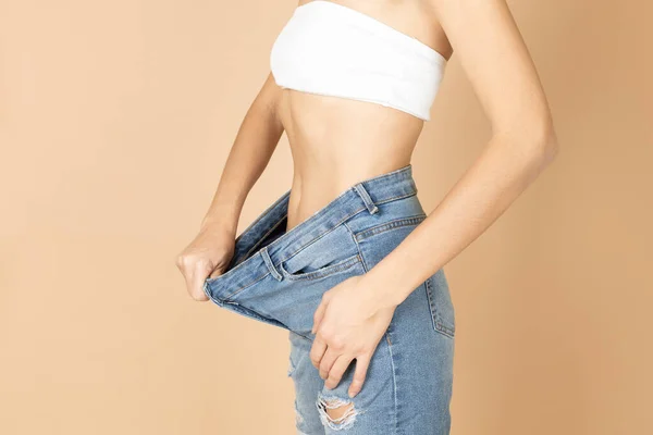 Mulher apta tendo rasgado jeans e sutiã branco em jeans de alongamento para mostrar barriga após a perda de peso. Manter a dieta e o exercício. Visando melhorar a saúde e se encaixar — Fotografia de Stock