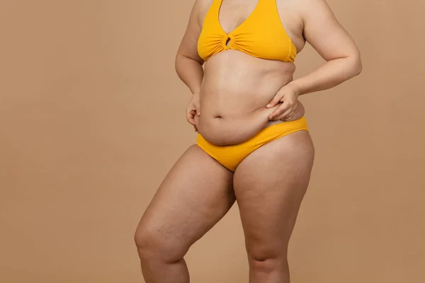 Gambar yang dipotong dari wanita gemuk, terselip, menyembunyikan lemak telanjang perut yang berlebihan besar di celana kuning. Dangling down perut, — Stok Foto