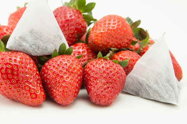 A pile of strawberries isolated over white background with tea bags on top — Stock Photo, Image