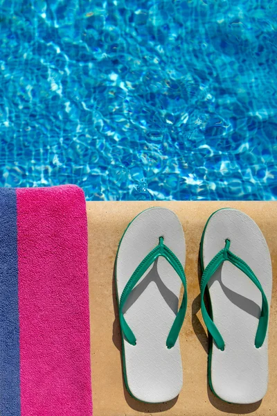 Paire de lanières flip flop et une serviette sur le côté d'une piscine — Photo