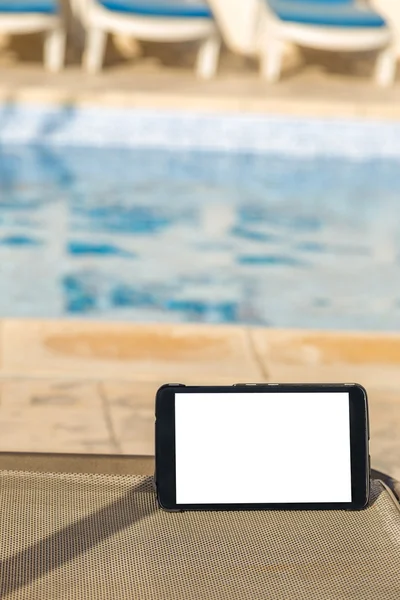 Tavoletta digitale vuota con spazio vuoto per testo su una sedia sul lato di una piscina — Foto Stock