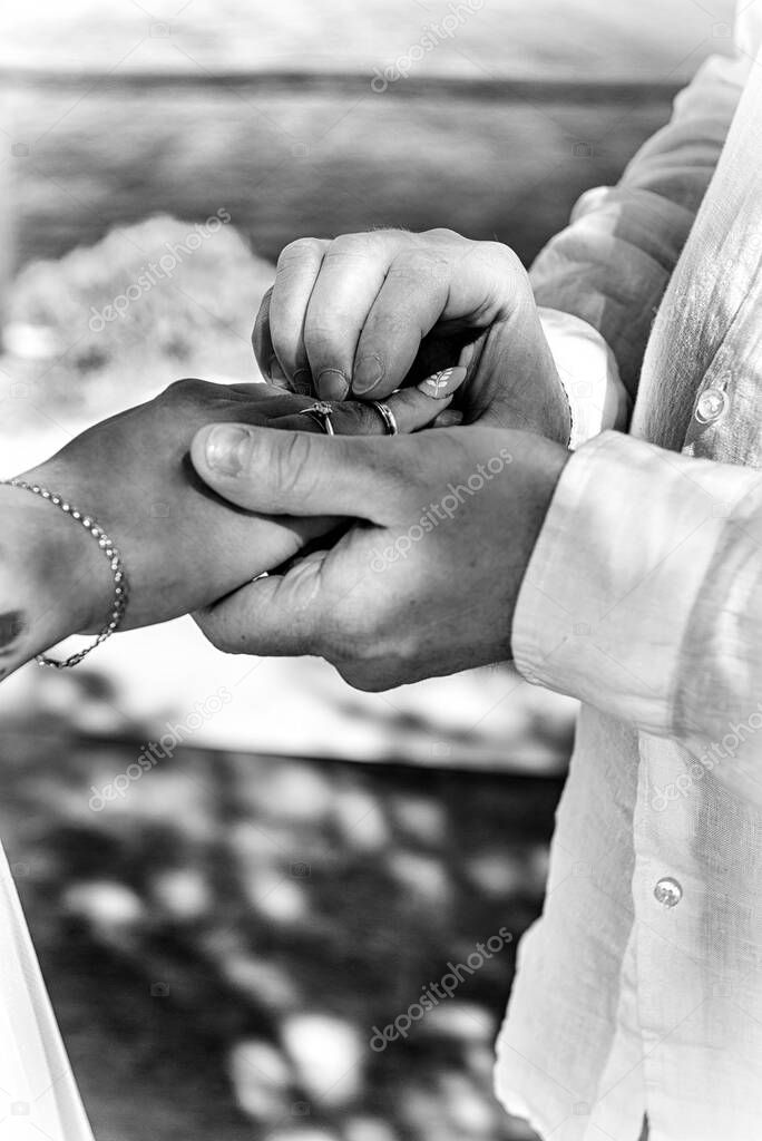 The groom places the ring on the bride's hand. Photo closeup. Black and white. Wedding details. 