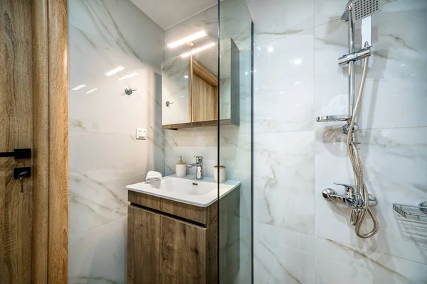 标准的现代化浴室室内设计 墙上的镜子 木制看台 用玻璃隔板隔开的淋浴器 大理石般的瓷砖墙 — 图库照片