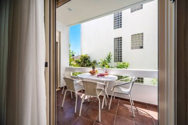 Mobilyalı balkon, fenerle süslenmiş beyaz masa, mumlar ve limon dalı, dört sandalye, güneşli yaz günü, tatil konsepti..