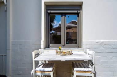 Balkon ya da teras konsepti. Beyaz ahşap masa ve pencerenin yanında iki sandalye..