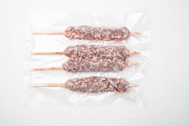 Süpürge paketindeki şişler üzerinde koyun eti kıyması, beyaz taş masa arkaplanı, üst görünüm düz.