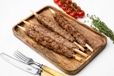 Baharatlı şişte ızgara Lula kebabı, arka planda beyaz taş masa.