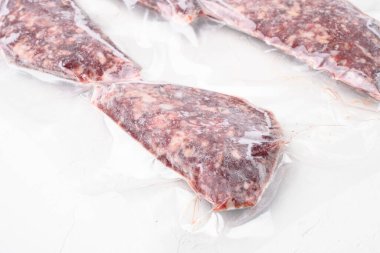 Süpürge eti ya da kuzu pirzolası. Beyaz taş masa arka planında hava geçirmez paket.