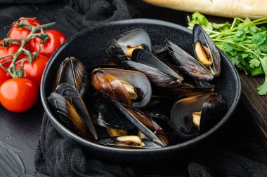 Klasik buharda pişirilmiş midye kabuklu, kaseli, siyah arka planda beyaz şarap.