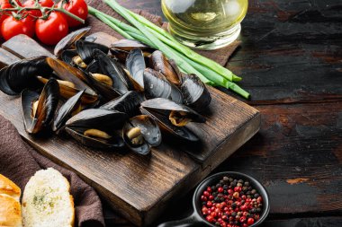 Peynir soslu ve sarımsak soslu haşlanmış midyeler, ahşap kesim tahtasının üzerinde, eski koyu ahşap masa zemininde, kopyalama alanı ve metin için yeri olan.