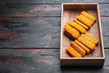 Çıtır balık parmakları ahşap kutuda, eski siyah tahta masa zemininde, kopyalanacak yer ve metin için yer var.