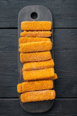 Donmuş balık kırıntıları seti, ahşap kesim tahtasına, siyah ahşap masa zeminine, üst manzara düz yatıyordu.