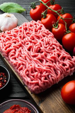 Bolonez sosu malzemelerini hazırlıyorum, kıyma, domates, ot seti, ahşap kesim tahtası üzerinde, siyah ahşap masa arkasında.