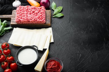 Lazanya hazırlığı için gerekli malzemeler. Domates, sos, Bechamel seti, siyah taş zemin üzerinde, metin için kopyalama alanı ile