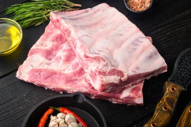 Organik çiftlikten taze çiğ domuz eti. Baharatlı, ballı, barbekü bıçaklı ve et çatallı. Siyah ahşap masa üzerinde.