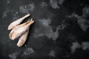 Donmuş Keçi Balığı çiğ balık seti, siyah taştan masa arkaplanı, üst görünüm düz, metin için kopyalama alanı var.