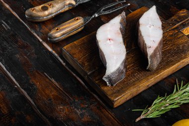 Çiğ balık bifteği seti, malzemeler ve biberiyeli, eski siyah ahşap masa zemininde, metin için fotokopi alanı var.