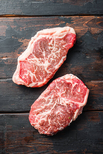 Raw marbled beef steak, top blade organic meat cut. On dark wooden background, top view