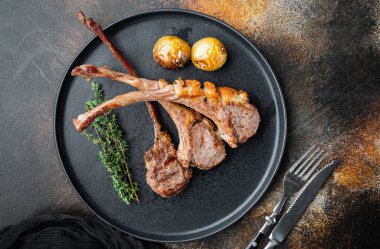 Izgara kuzu kaburga fileto seti, tabakta, eski koyu rustik arka planda, üst görünüm düz yerde, metin için kopyalanacak yeri ve yeri var