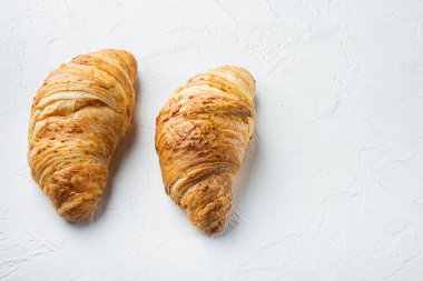 Beyaz taş zemin üzerinde taze kruvasan seti, metin için kopyalama alanı var.