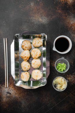 Konteynırlarda suşi rulolarını, Philadelphia rulolarını ve fırınlanmış karides rulolarını alıp götür, eski, koyu kırsal arka planda, üst görünüm düz yatağında, metin için metin alanı ve boşluğu ile