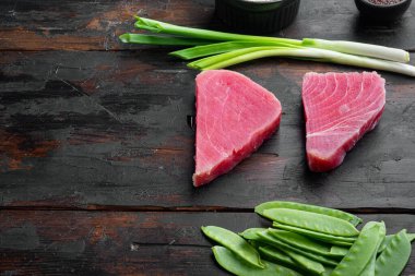 Çiğ susamlı ton balığı bifteği seti, eski koyu ahşap masa arka planında, metin için metin alanı ve boşluk ile.