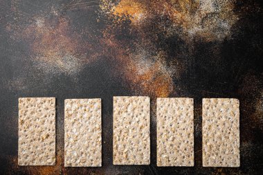 Tam tahıllı çavdar ekmeği kraker seti, eski koyu rustik masa arkaplanı, üst görünüm düz, metin alanı için kopyalama alanı ile