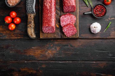 Dilimlenmiş salam seti, eski koyu ahşap masa arkaplanı, üst görünüm düz yatay, metin için kopyalama alanı ile