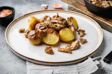 Mantarlı kızarmış patates, gri masa arkasında.