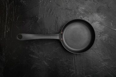 Metin ya da yiyecek için metin ya da yiyecek için kopyalama alanı olan büyük tava seti, üst görünüm düz, siyah taş masa arkaplanı üzerinde