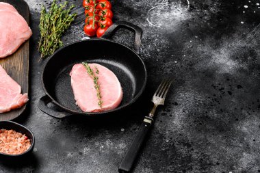 Çiğ organik et. Domuz bifteği, ızgara, pişirme ya da kızartma seti için fileto, kızarmış demir tavada, siyah taş masa arkasında, metin için kopyalama alanı ile birlikte.