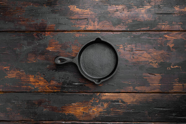 Чугунная сковородка с копировальным местом для текста или еды с копировальным местом для текста или еды, плоский вид сверху, на старом темном деревянном столе