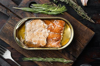 Vahşi Alaska Somonu Tütsülenmiş balık seti, ahşap kesme tahtası, eski, siyah ahşap masa zemininde otlar ve malzemeler, üst manzara düz