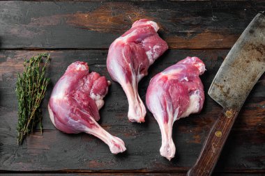 Çiftlikten yeni çıkmış organik çiğ ördek bacağı. Eski bir kasap bıçağı, eski bir ahşap masa zemininde. Üst manzara düz.