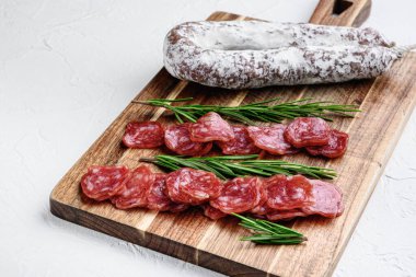 Beyaz desenli arka planda bütün ve dilimlenmiş İspanyol kuru sosisi..