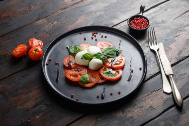 Domates, fesleğen, mozzarella Caprese salatası, balzamik sirke ve zeytinyağı. eski tahta arka plan.