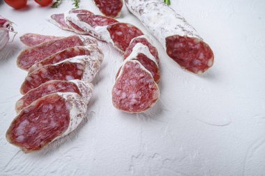 Kurutulmuş et salamı sosisleri beyaz yüzeyde otlarla birlikte fotokopi alanı ile birlikte dilimler..