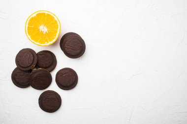 Jaffa Kekleri. Çerezler koyu çikolatayla kaplı ve içi turuncu marmelat setiyle dolu, beyaz taş masa zemininde, üst görünümü düz, metin alanı için fotokopi alanı var.