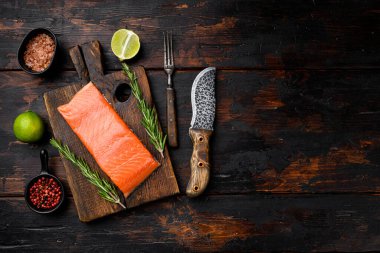 Somon balığı. Taze çiğ somon balığı fileto seti, bitkilerle birlikte, eski koyu ahşap masa arkaplanı üzerinde, üst görünüm düz, metin alanı için kopyalama alanı ile