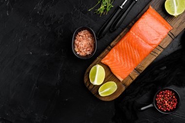Taze çiğ somon seti, otlarla birlikte, siyah taş masa zemininde, üst görünüm düz, metin alanı için kopyalama alanı ile