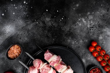 Şiş seti üzerinde bir barbekü salamurasında et, üst görünüm düz, metin için kopya alanı, siyah koyu taş masa arka planında